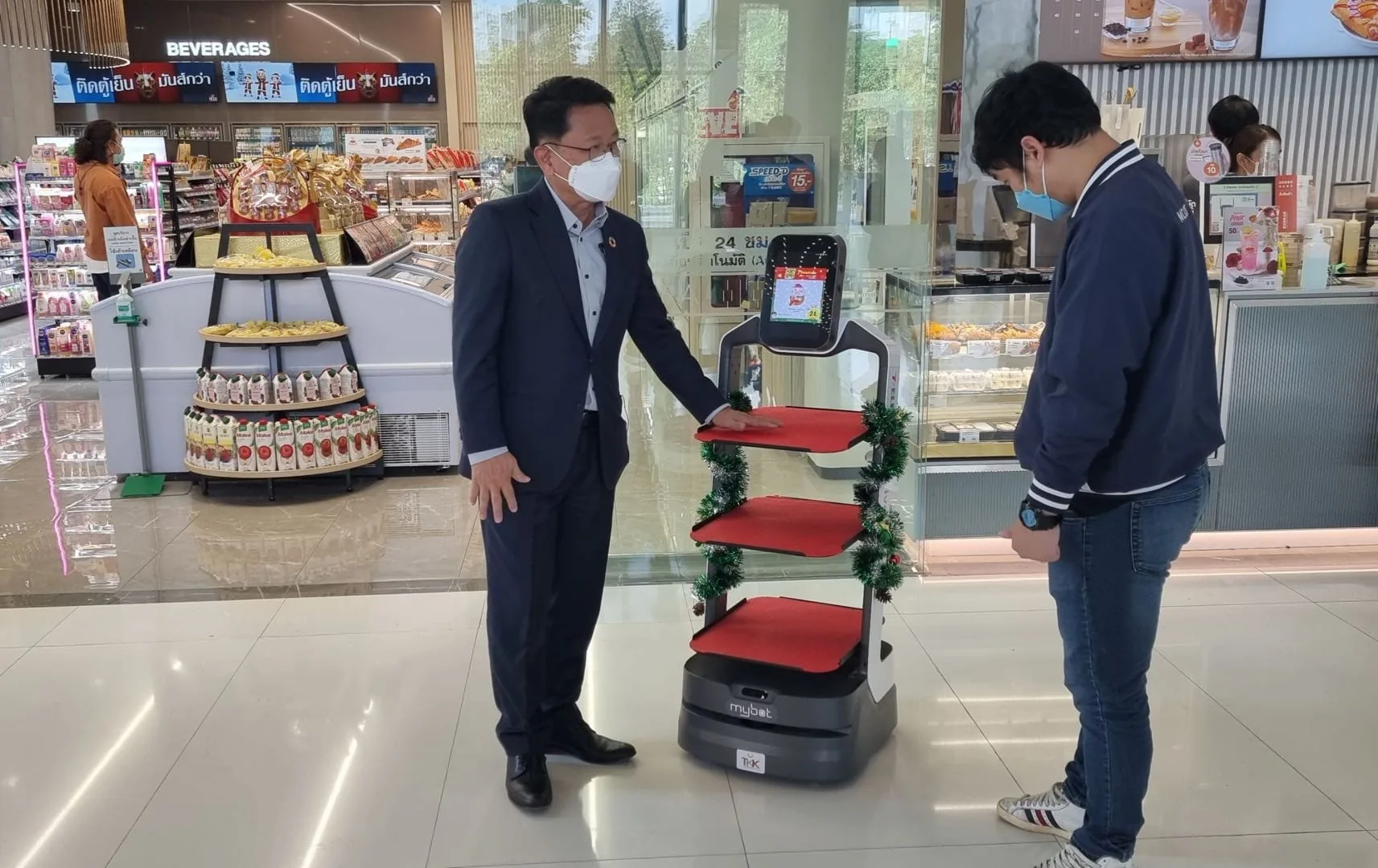 Robot LuckiBot con contenido publicitario en la pantalla atendiendo a dos visitantes en un centro comercial