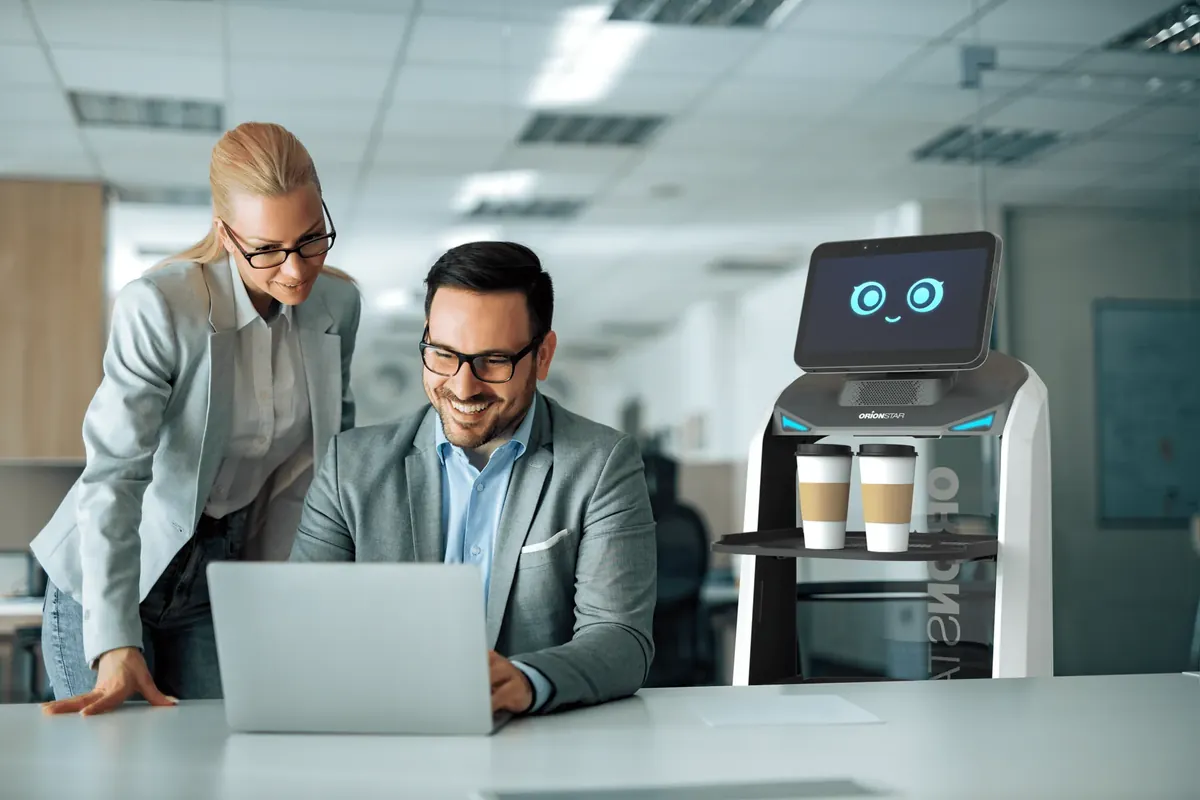 Robot de servicio entregando cafés a dos empleados en una oficina